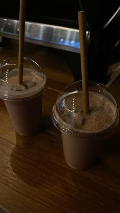 two plastic cups with straws in them sitting on a table