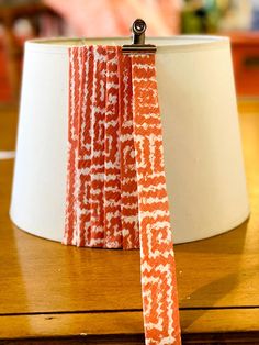 an orange and white tie sitting on top of a wooden table next to a lamp