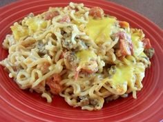 a red plate topped with pasta covered in cheese and meat sauce on top of it