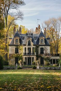 an old style house in the fall with lots of leaves on the ground and trees around it