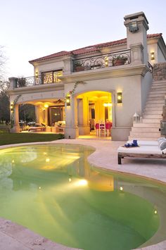 a large house with a pool in the front yard and stairs leading up to it