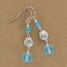 two sea glass beads hang from silver earwires on a brown surface with a pair of earrings