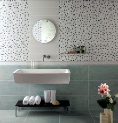 a white sink sitting under a bathroom mirror next to a vase with flowers in it