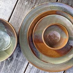 three brown and green plates sitting on top of a wooden table