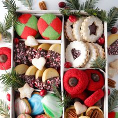 a box filled with different types of cookies and candies next to pine cones on top of a table