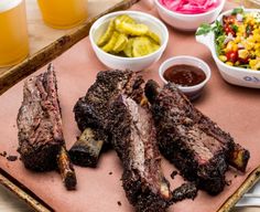 a tray with ribs, salad and drinks on it