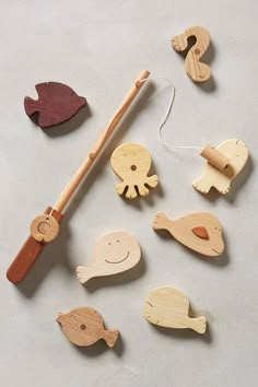 various wooden toys are arranged on a white surface, including a fishing rod and fish