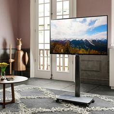 a flat screen tv sitting on top of a wooden stand in a living room next to a window