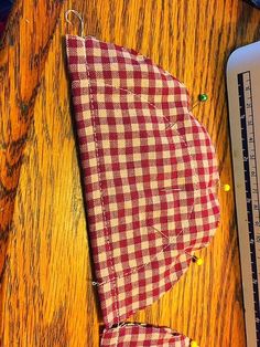 a piece of red and white checkered fabric next to a ruler on a wooden table