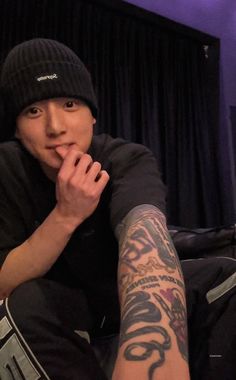 a man sitting on the floor with his hand under his chin and wearing a beanie