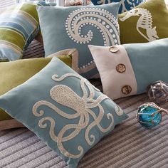 decorative pillows on a bed with seahorses and shells