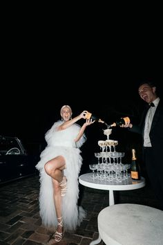 a man and woman standing next to each other near a table with wine glasses on it