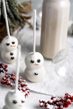 marshmallow snowmen are sitting in the snow with candy sticks sticking out of them