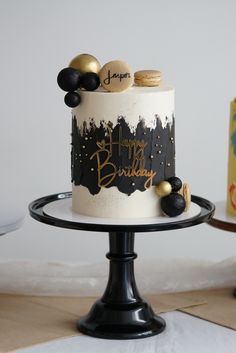 a birthday cake sitting on top of a black and white plate next to a box of cookies