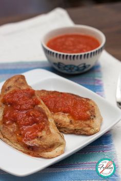 two pieces of bread covered in sauce on a plate with a spoon next to it