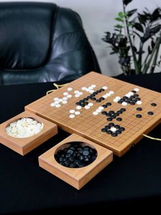 a wooden board game set with black and white pieces on it next to a leather chair