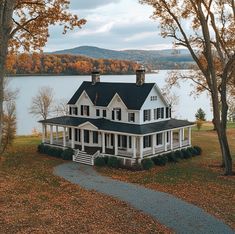 a large white house sitting on top of a lush green field next to a lake