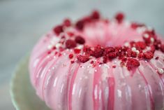 a pink cake with white and red sprinkles sitting on top of a plate