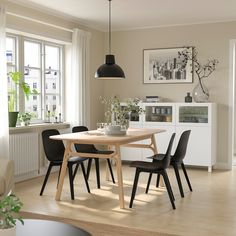 a dining room table and chairs in front of a window with potted plants on it