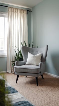 a living room with a chair, rug and potted plant on the floor in front of a window