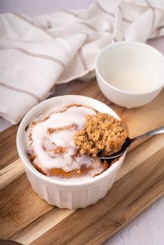 a bowl filled with food sitting on top of a wooden cutting board next to a spoon