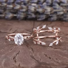 two rose gold wedding rings with white diamonds on top of each other, sitting on a piece of wood