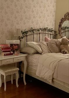 a white bed sitting next to a table with a mirror on it's side