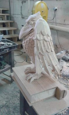 a sculpture of an owl sitting on top of a piece of wood in a workshop