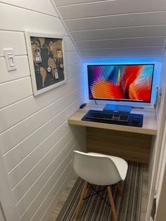 a desk with a computer on it in a room that has white walls and wood floors