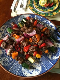 a blue and white plate topped with meat and veggies next to a fork