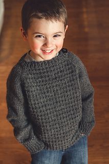 a young boy wearing a sweater and smiling