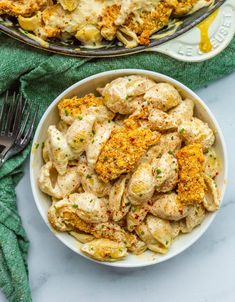 two bowls filled with chicken and pasta next to a green towel on the counter top