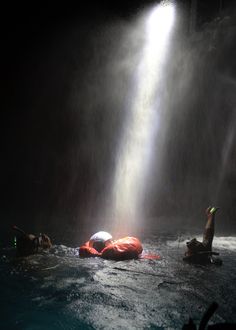 some people are in the water and one is floating on an raft under a waterfall