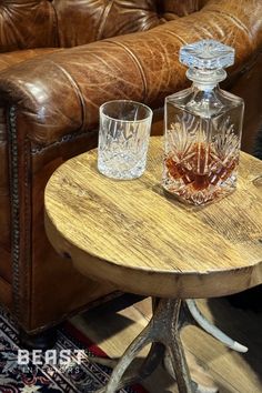 two whiskey glasses sitting on top of a table next to a brown leather couch in a living room