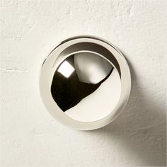 a shiny chrome door knob on a white wall