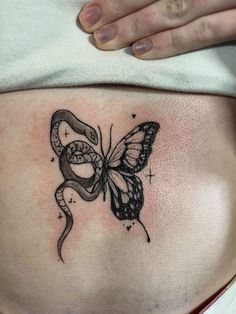 a woman's stomach with a butterfly and snake tattoo on the side of her belly