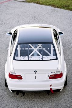 the back end of a white car parked in a parking lot