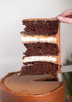 someone is cutting into a chocolate cake with white frosting on the top and bottom