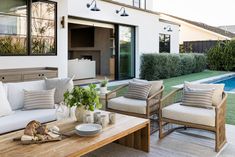 an outdoor living area with couches, tables and chairs next to a swimming pool