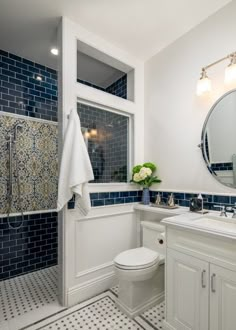 a white toilet sitting next to a bathroom sink under a large mirror on top of a wall