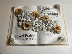 an open book with paper flowers on it