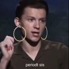 a man wearing large gold hoop earrings on his face in front of a dark background