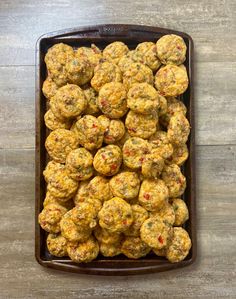 a brown tray filled with meatballs on top of a wooden table next to a knife