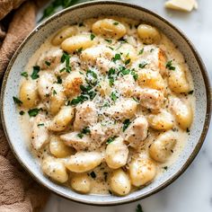 a bowl filled with pasta and chicken covered in gravy on top of a table