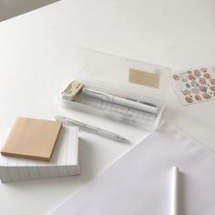 a pen and some papers on top of a white table next to an envelope with stickers