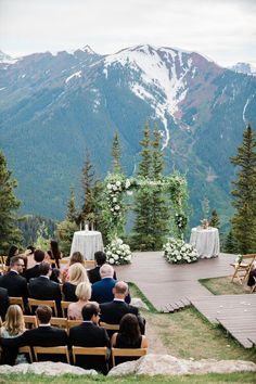 an outdoor ceremony in the mountains with people sitting on chairs and looking at each other