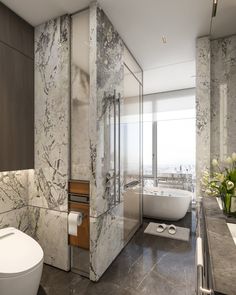 a bathroom with marble walls and flooring next to a bathtub