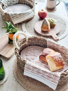 some bread is sitting in a wicker basket on a table with other food items