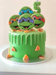 a green cake with two teenage mutant cakes on it's top and one is decorated like a turtle