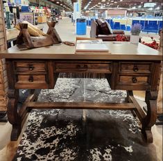 a wooden table sitting inside of a store next to a cowhide rug and leather couch